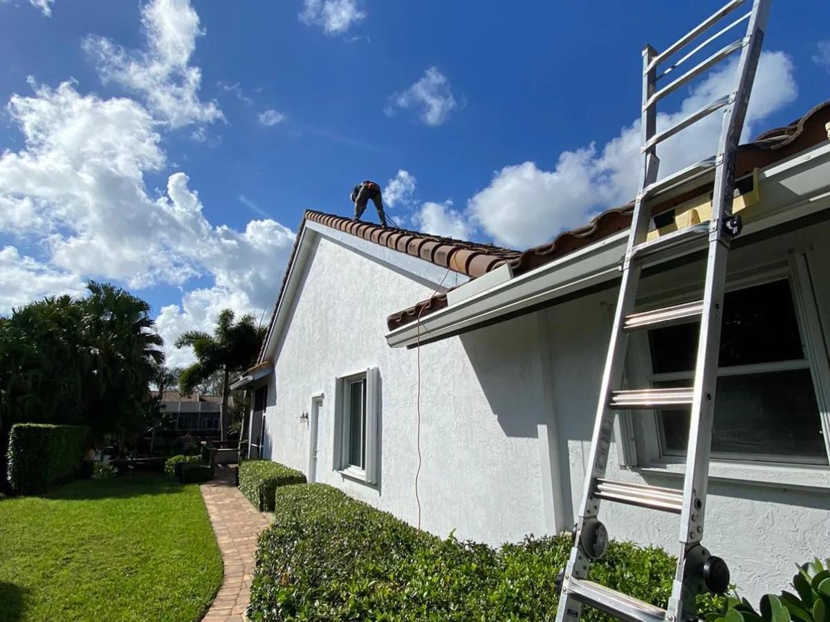Roofer on tile roof with ladder at residential home in Pembroke Pines, FL — Broward Roofing Pros